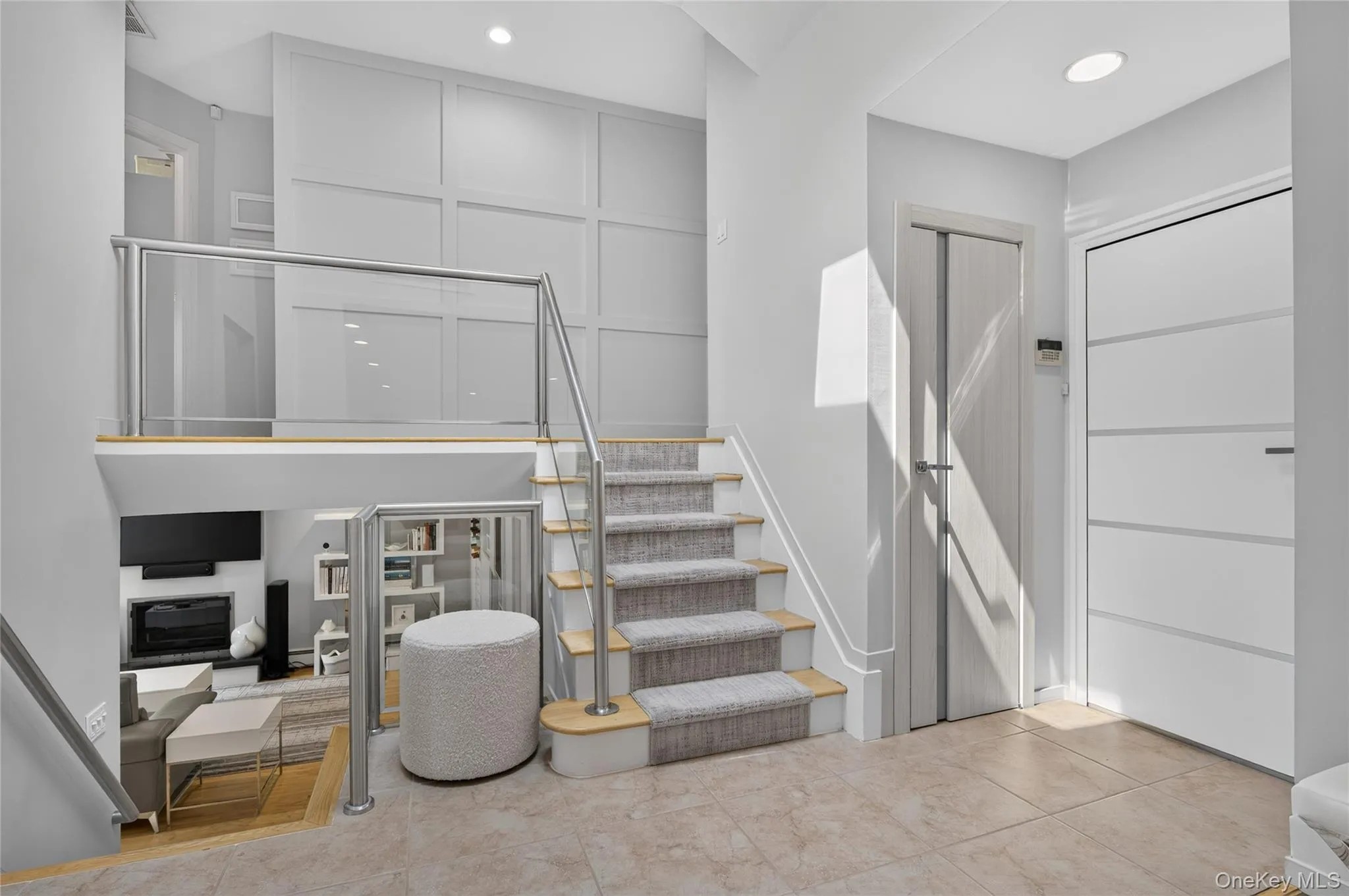 Entryway featuring an accent wall, carpeted staircase with wood-finish risers and glass-panel railings Entryway featuring an accent wall, carpeted staircase with wood-finish risers and glass-panel railings