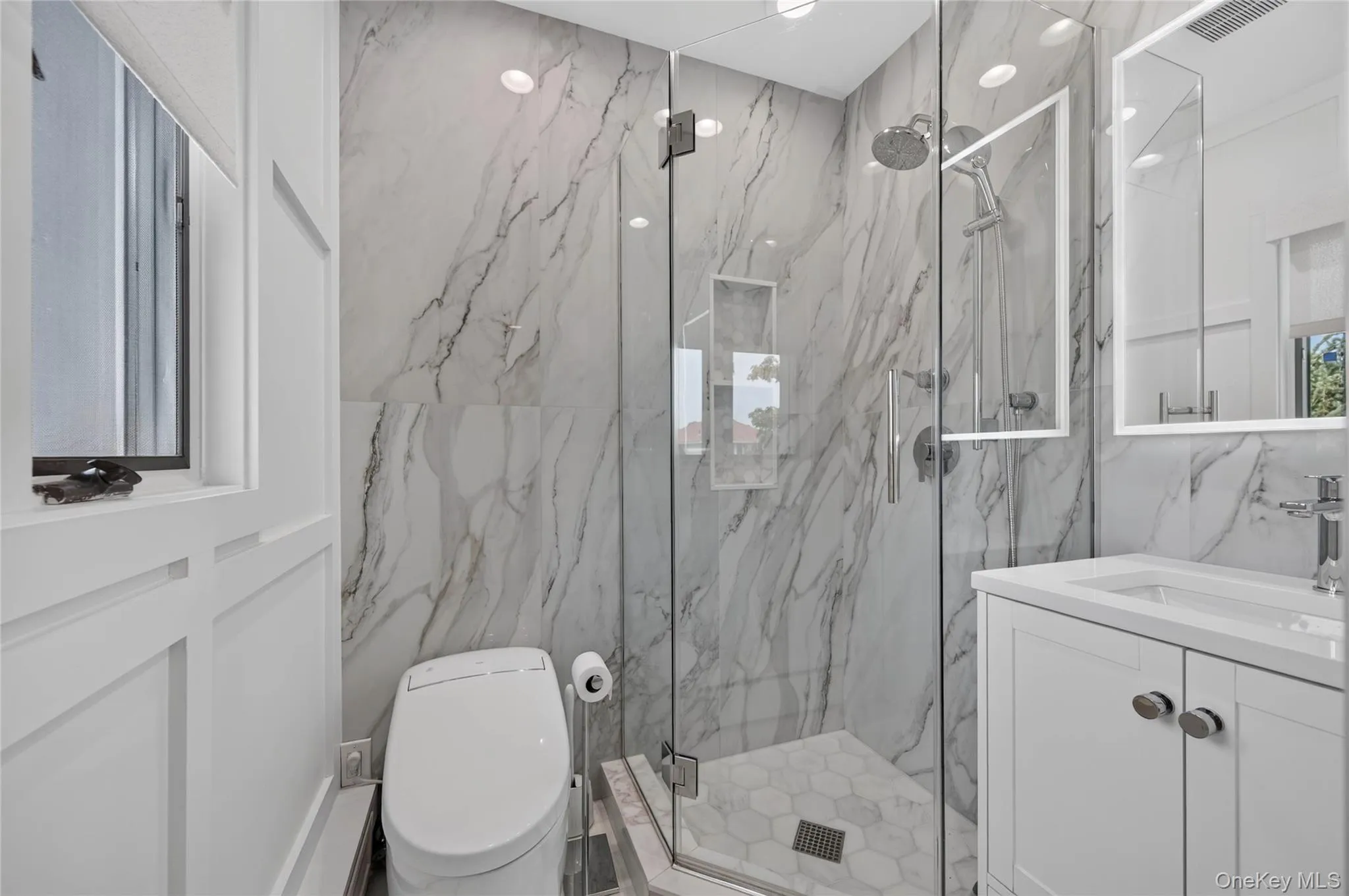 Renovated primary bathroom with glass-enclosed shower and built-in niche Renovated primary bathroom with glass-enclosed shower and built-in niche