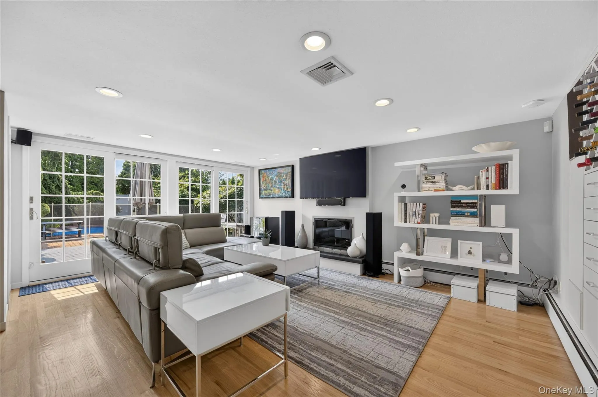 Living area featuring light wood-finish flooring, recessed ceiling lighting, and a fireplace Living area featuring light wood-finish flooring, recessed ceiling lighting, and a fireplace