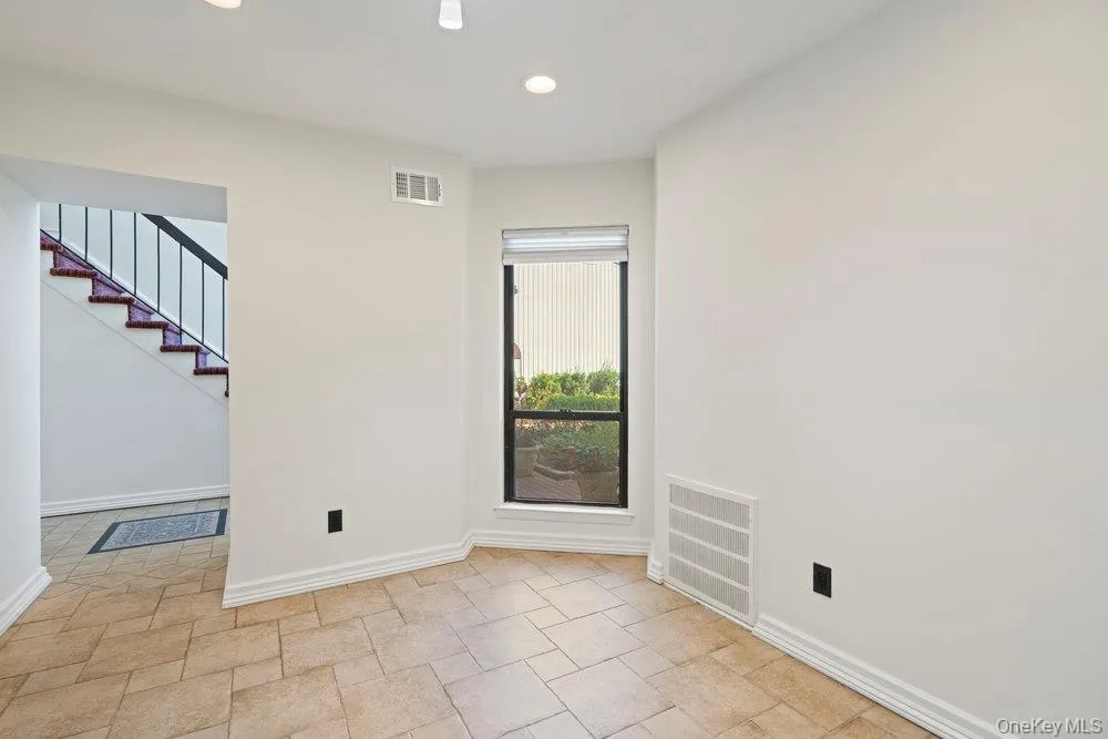Tiled flooring throughout this space, featuring a corner window with blinds, recessed lighting, and white baseboards Tiled flooring throughout this space, featuring a corner window with blinds, recessed lighting, and white baseboards