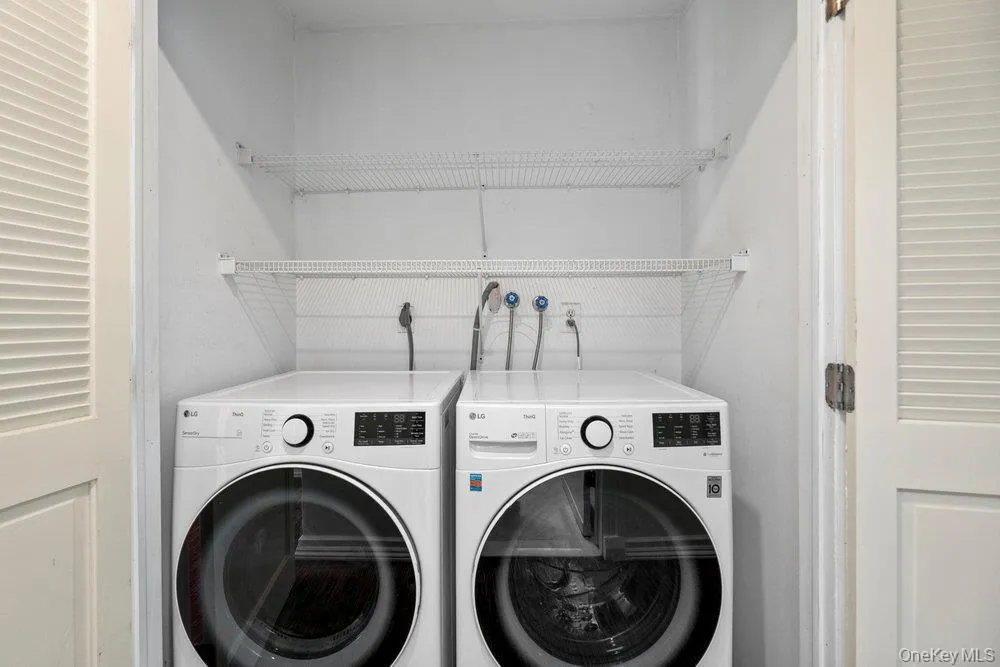 Dedicated laundry closet featuring a stackable washer and dryer, louvered bi-fold doors, and integrated wire shelving Dedicated laundry closet featuring a stackable washer and dryer, louvered bi-fold doors, and integrated wire shelving