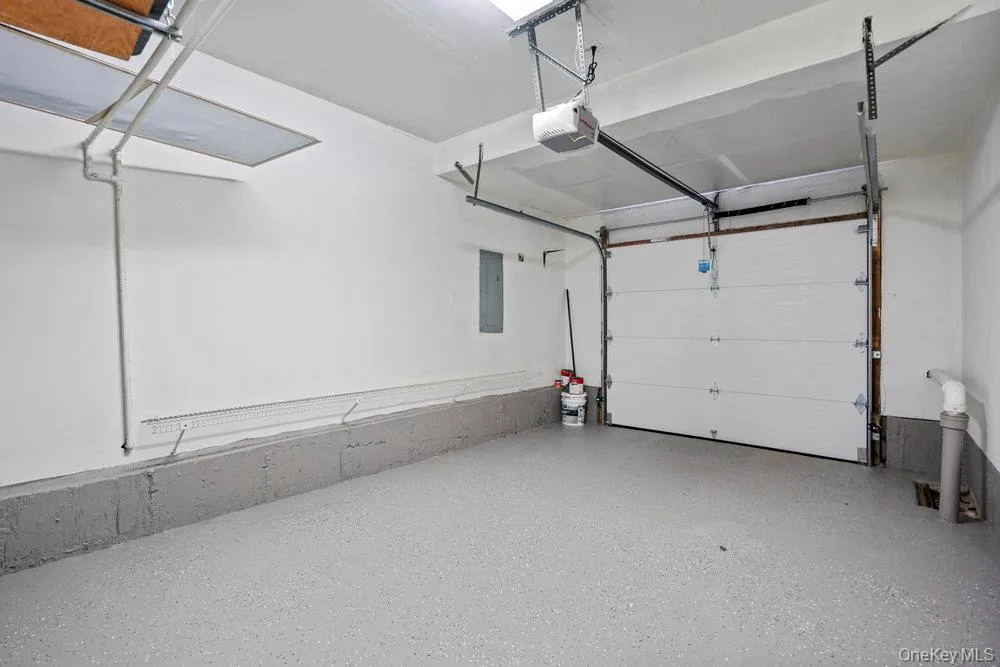 Single-car garage featuring a painted concrete floor, white walls, and an automatic garage door opener Single-car garage featuring a painted concrete floor, white walls, and an automatic garage door opener