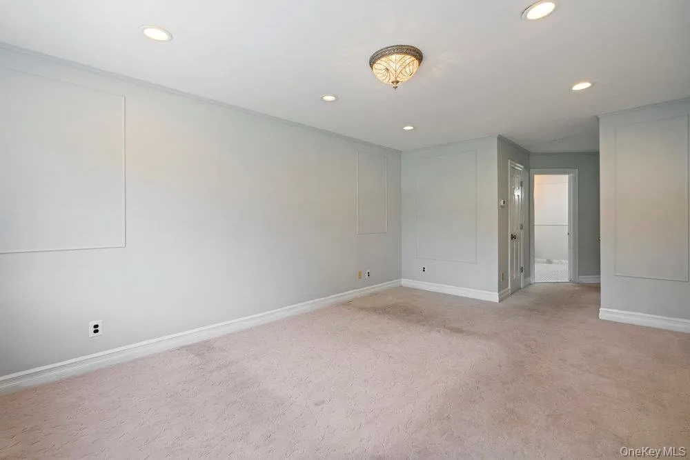 Carpeted room, that will be changed to wood flooring, featuring recessed lighting, a decorative ceiling fixture, and wall paneling details Carpeted room, that will be changed to wood flooring, featuring recessed lighting, a decorative ceiling fixture, and wall paneling details