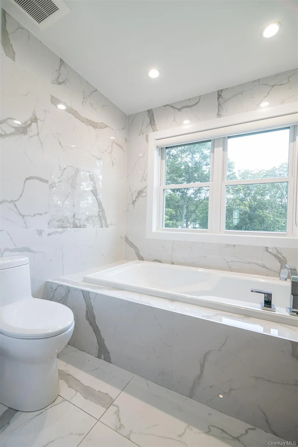 Full bath with a bath, light marble finish flooring, tile walls, stone wall, and recessed lighting Full bath with a bath, light marble finish flooring, tile walls, stone wall, and recessed lighting