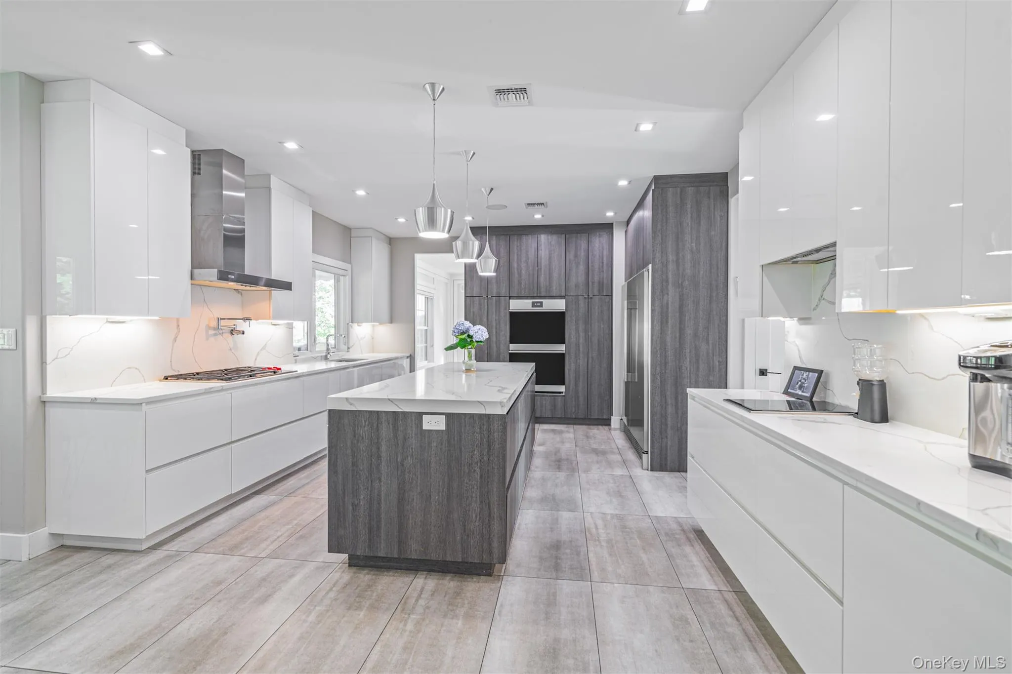 Kitchen featuring modern cabinets, white cabinetry, backsplash, light stone countertops, and recessed lighting Kitchen featuring modern cabinets, white cabinetry, backsplash, light stone countertops, and recessed lighting