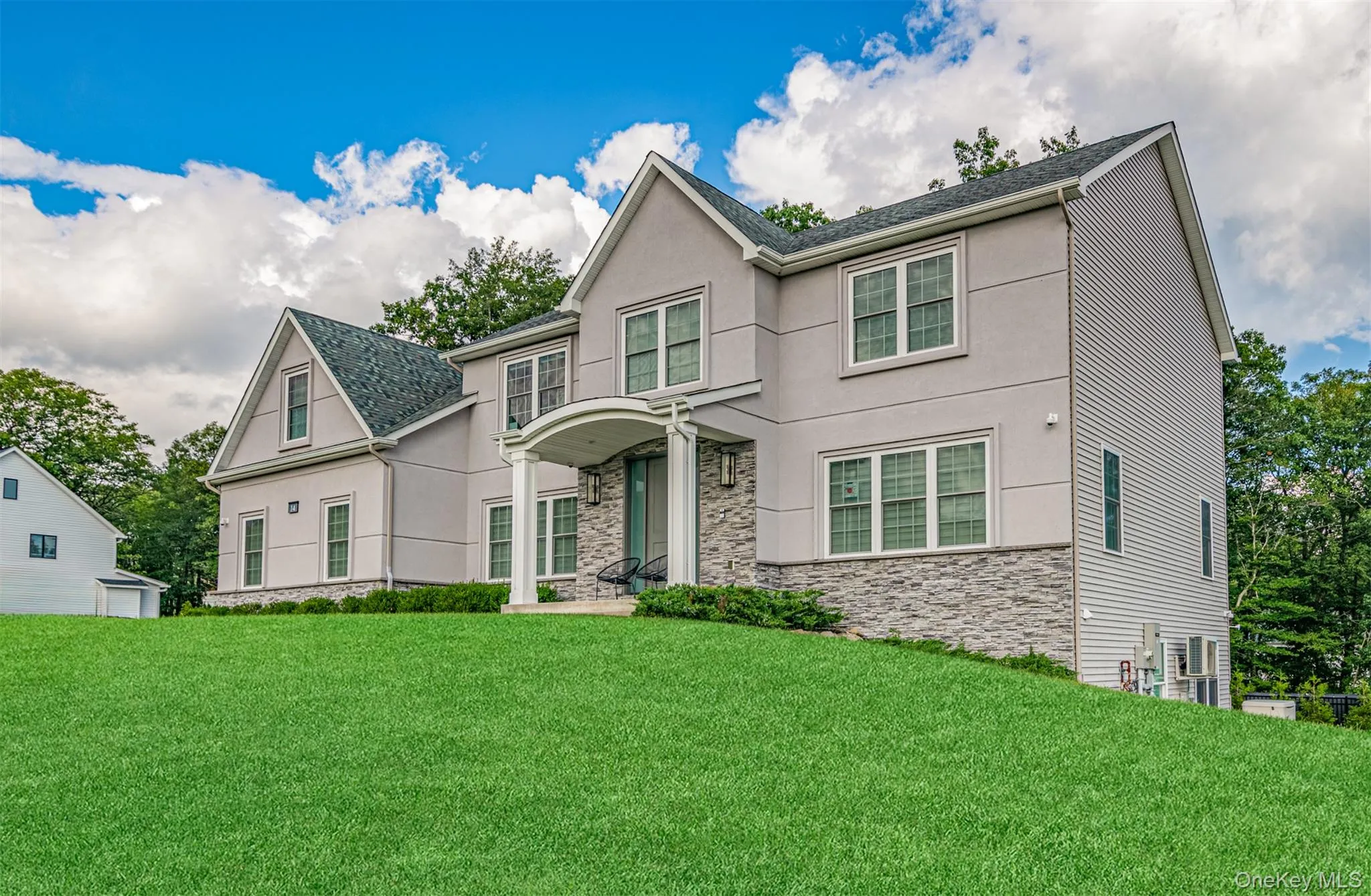 View of front of house featuring stone siding, a front lawn, and stucco siding View of front of house featuring stone siding, a front lawn, and stucco siding