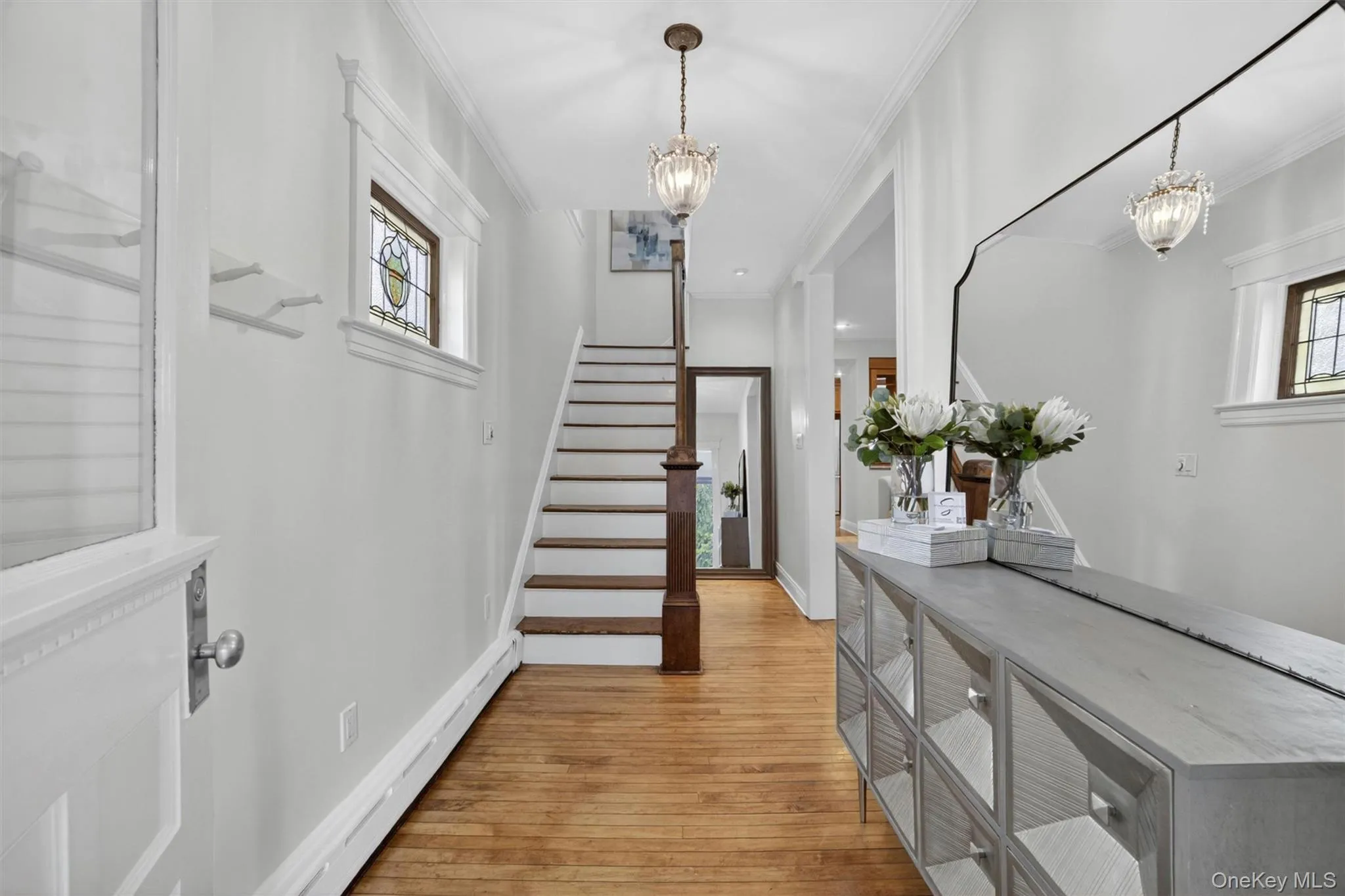 Inviting entryway featuring wood-finish flooring and a staircase with a dark wood handrail Inviting entryway featuring wood-finish flooring and a staircase with a dark wood handrail