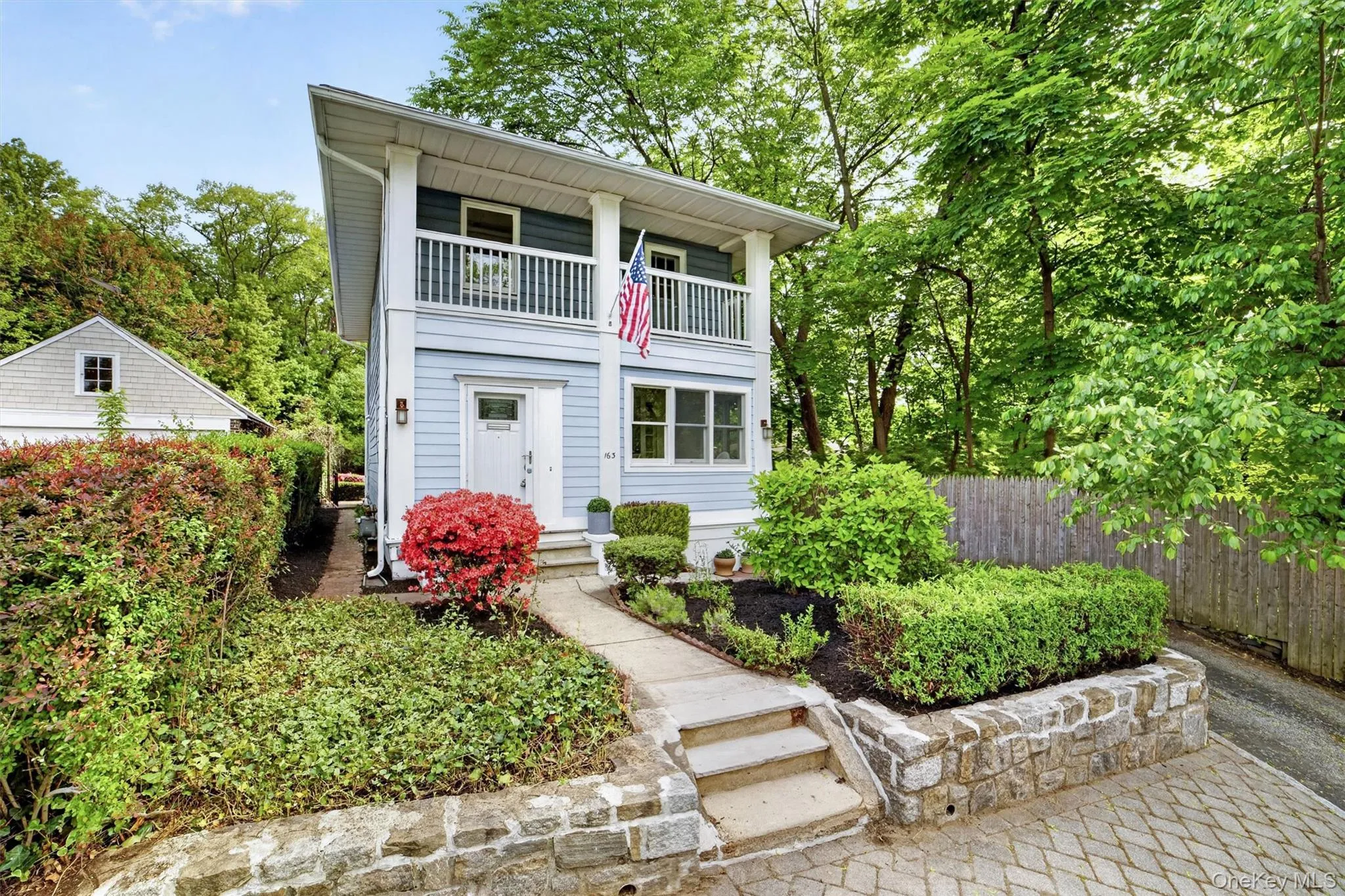 Light blue siding exterior with a second-story balcony featuring white railings Light blue siding exterior with a second-story balcony featuring white railings