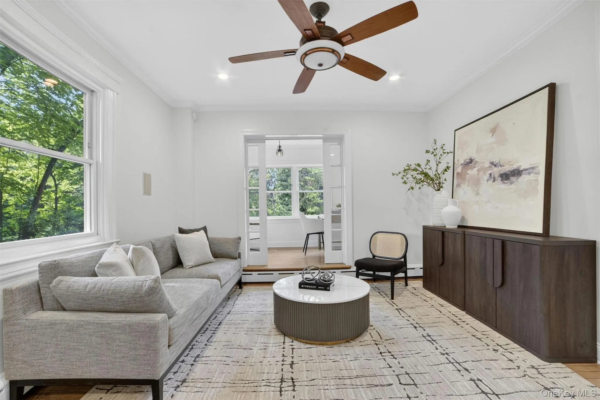 Bright living area featuring wood-finish flooring, a contemporary ceiling fan, and white crown molding Bright living area featuring wood-finish flooring, a contemporary ceiling fan, and white crown molding
