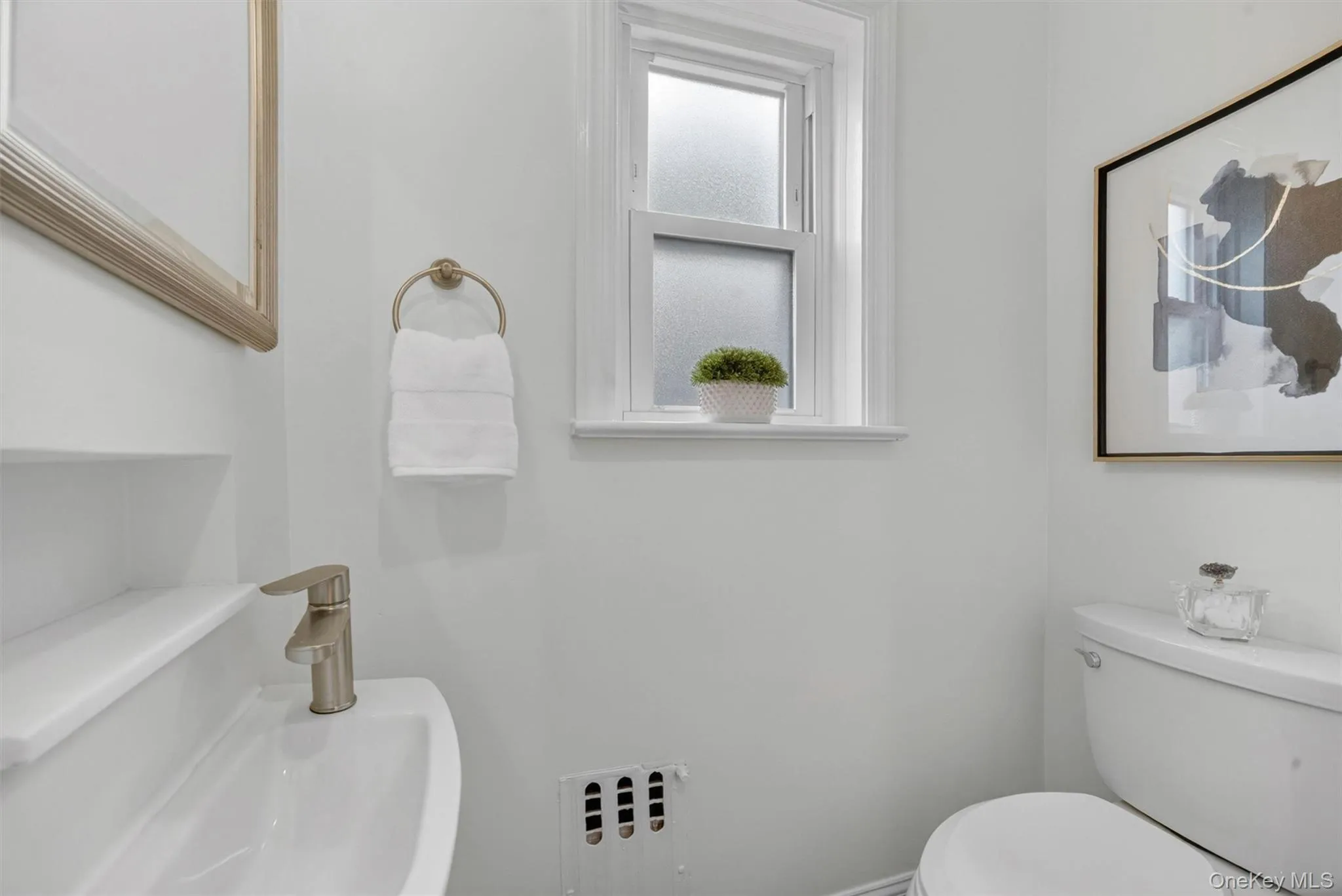 Powder room featuring a wall-mounted sink with a brushed nickel faucet, a white toilet, and a window with privacy glass Powder room featuring a wall-mounted sink with a brushed nickel faucet, a white toilet, and a window with privacy glass
