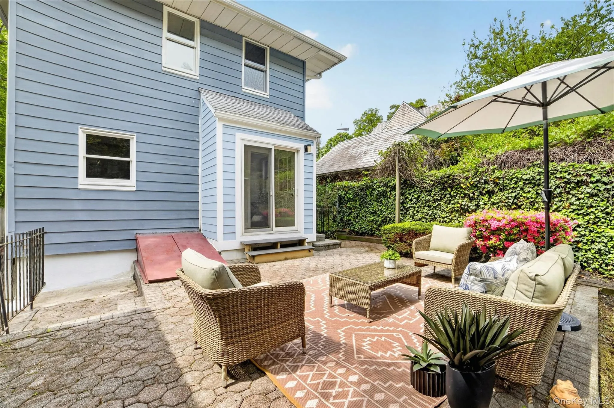 Stone paver patio featuring a sliding glass door entry and blue clapboard siding Stone paver patio featuring a sliding glass door entry and blue clapboard siding