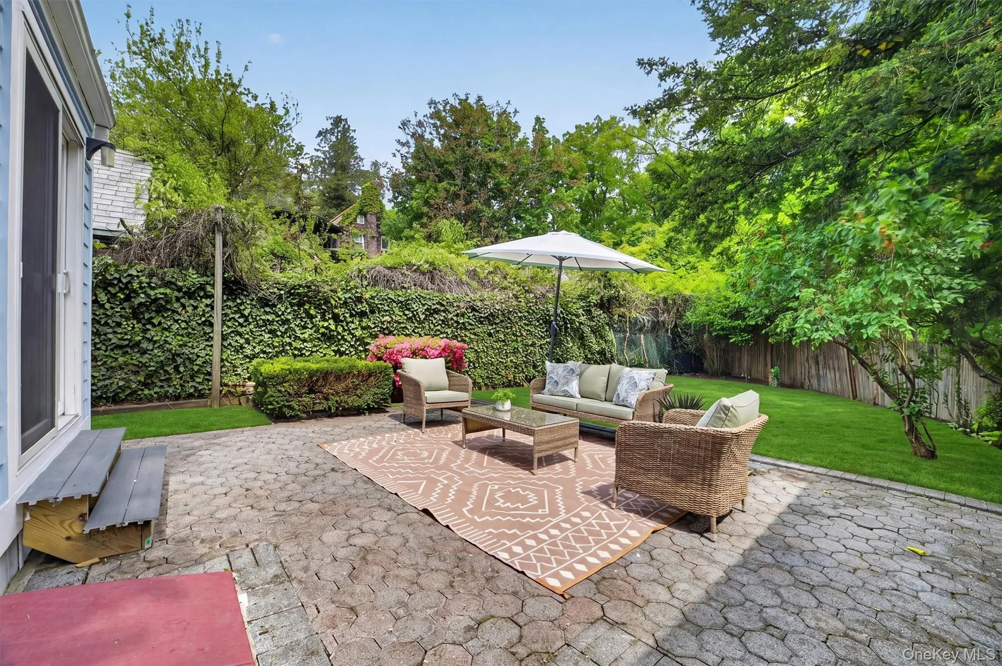 Stone paver patio with a surrounding manicured lawn and mature trees Stone paver patio with a surrounding manicured lawn and mature trees