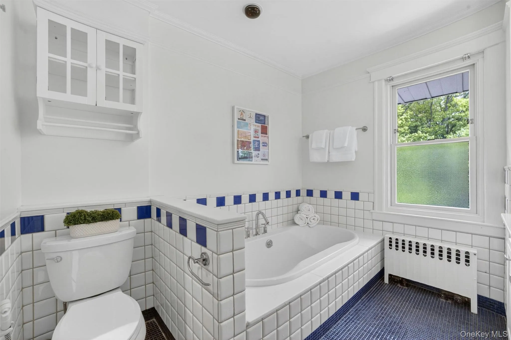 Bathroom featuring a built-in tub, white subway tile walls with blue accents, and blue mosaic floor tile Bathroom featuring a built-in tub, white subway tile walls with blue accents, and blue mosaic floor tile