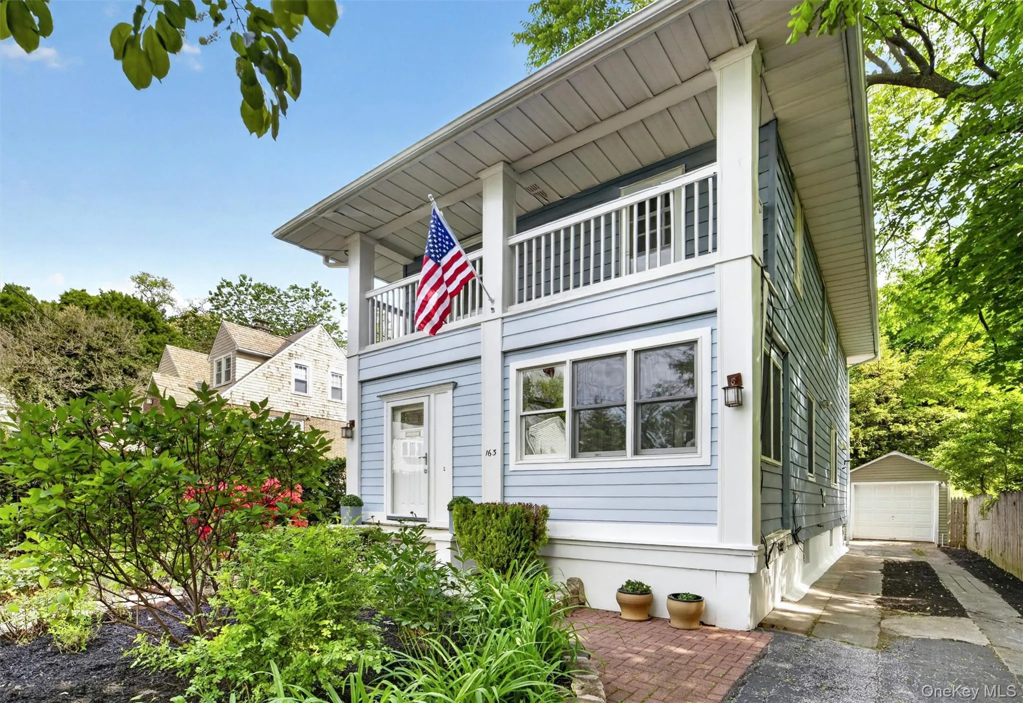 Light blue siding exterior featuring a covered porch, upper-level balcony, and white balustrade Light blue siding exterior featuring a covered porch, upper-level balcony, and white balustrade
