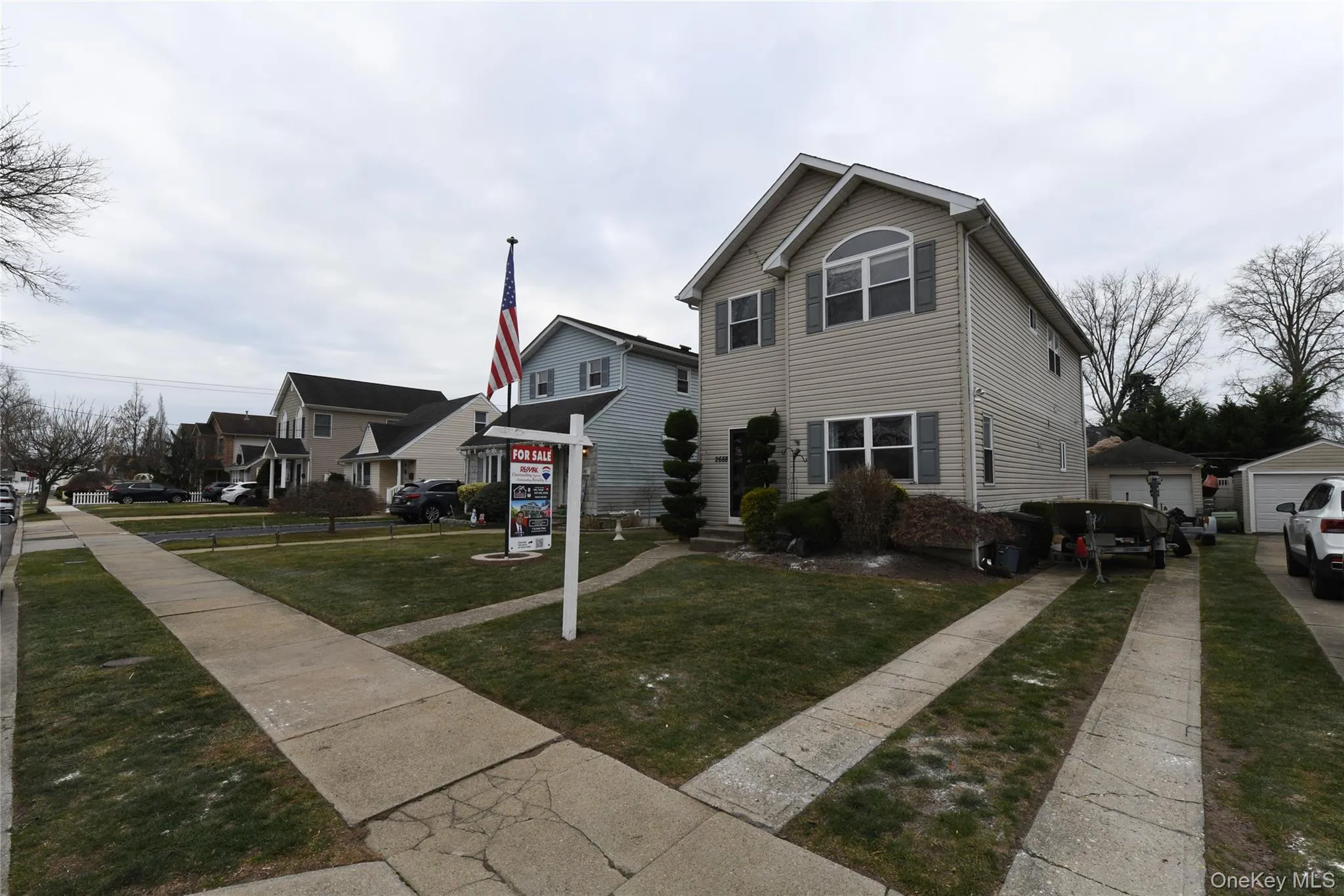 View of front facade with a front yard, a residential view, and a detached garage View of front facade with a front yard, a residential view, and a detached garage