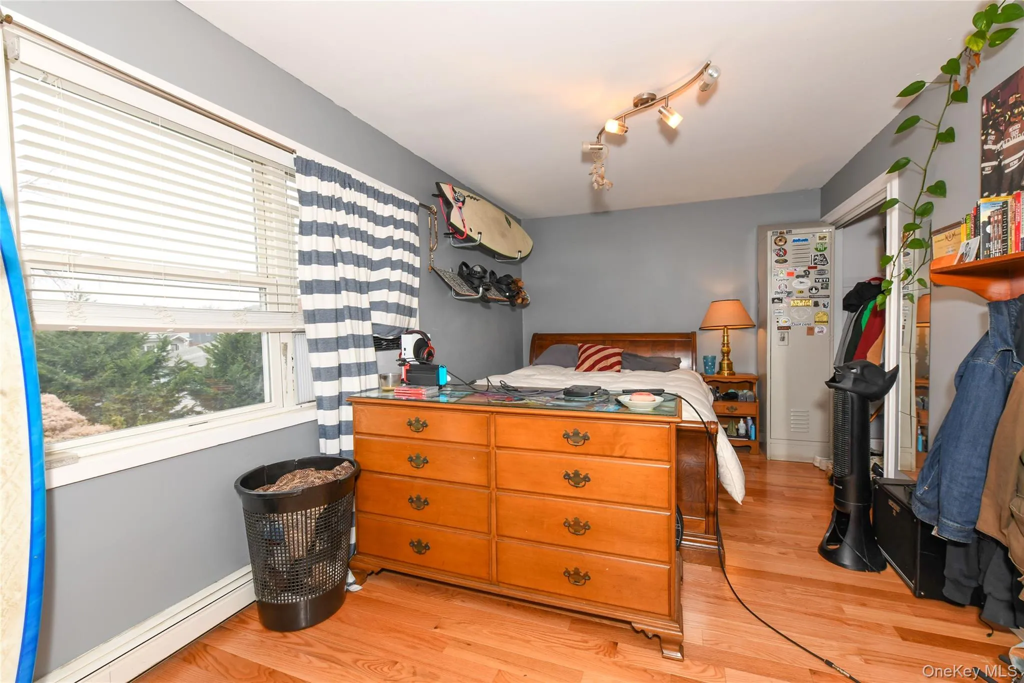 Bedroom featuring baseboard heating, light wood-style floors, and track lighting Bedroom featuring baseboard heating, light wood-style floors, and track lighting