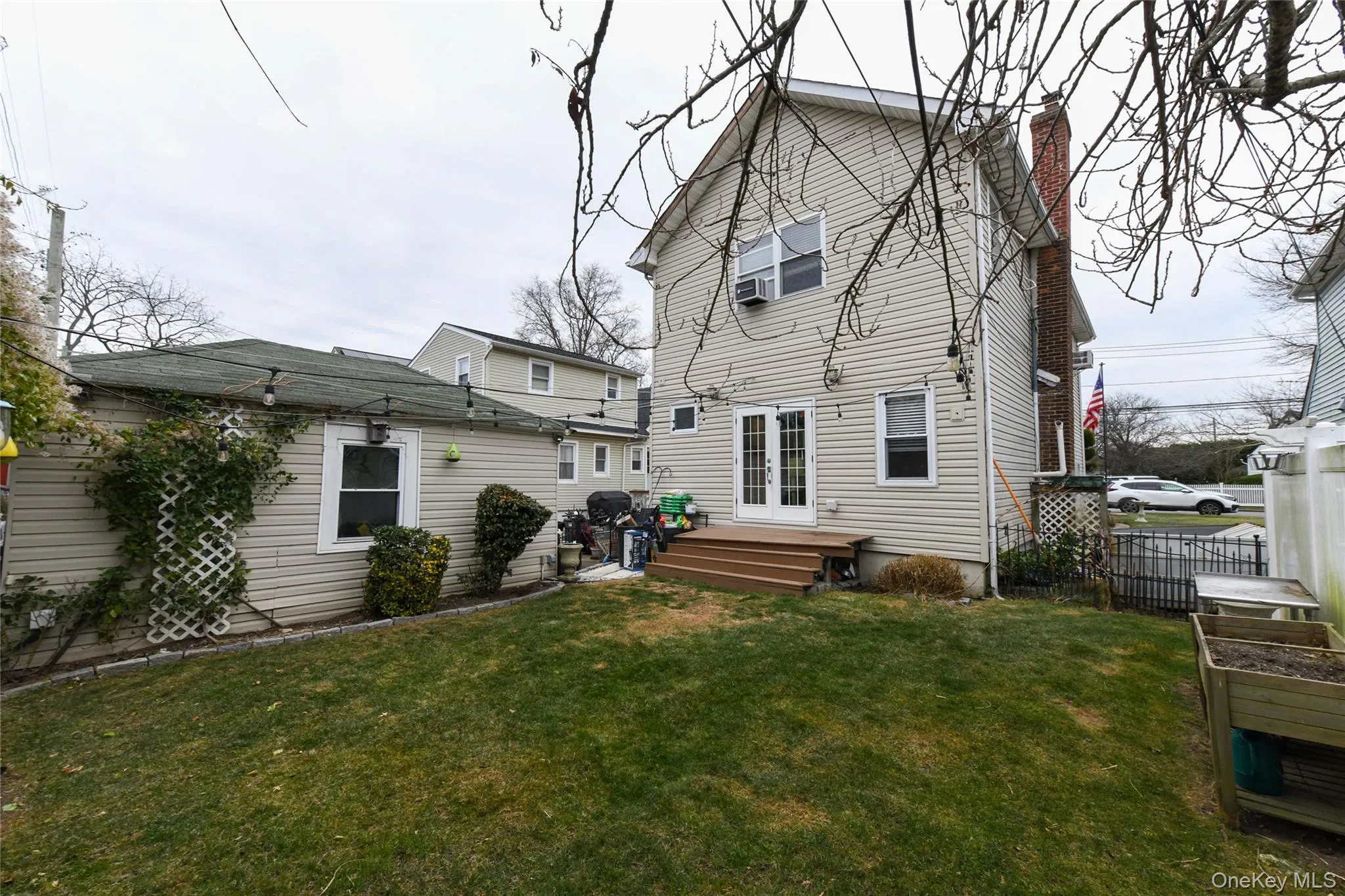 Rear view of house featuring a wooden deck, a chimney, and french doors Rear view of house featuring a wooden deck, a chimney, and french doors