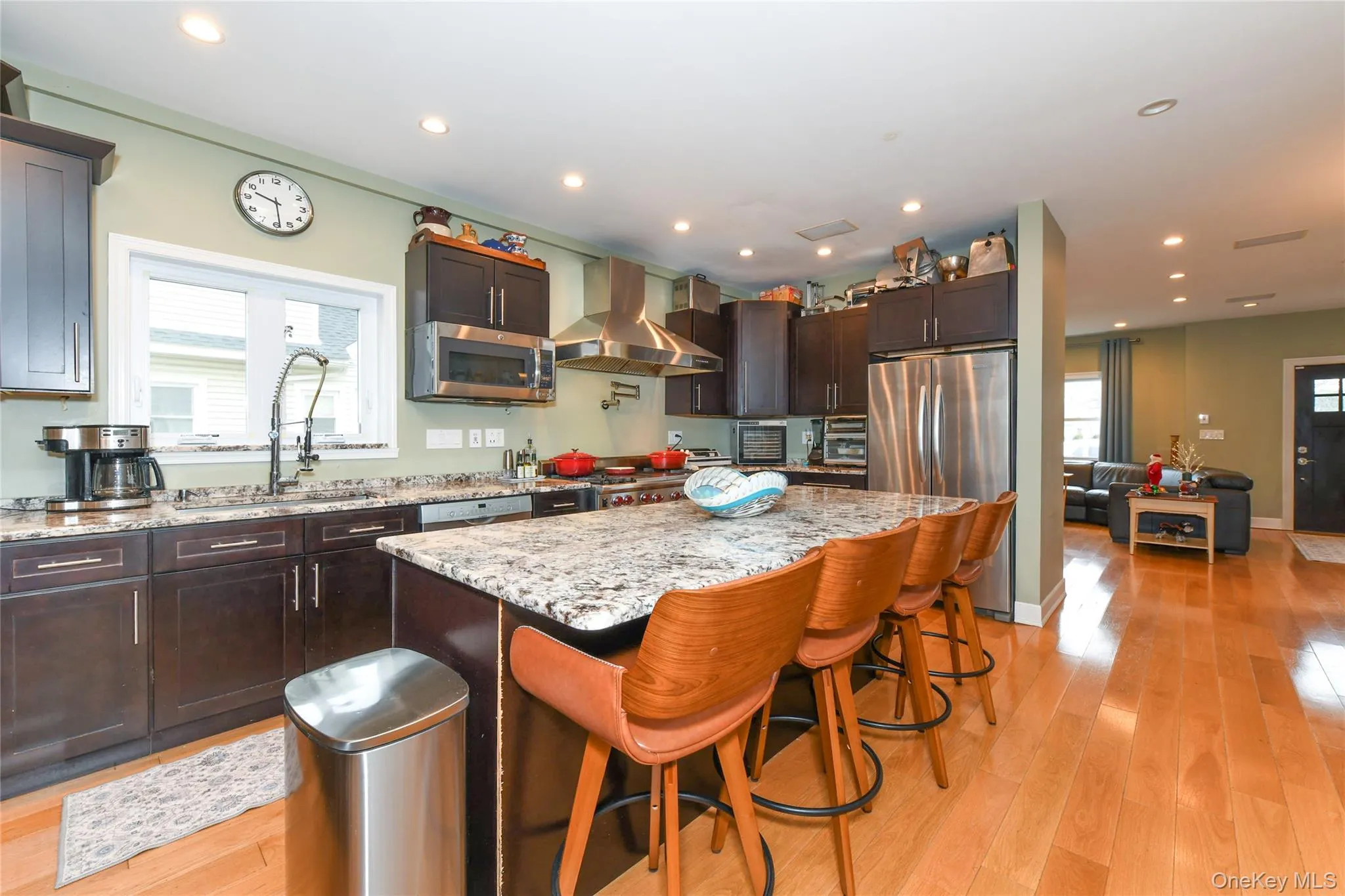 Kitchen with a kitchen bar, ventilation hood, light stone countertops, appliances with stainless steel finishes, and recessed lighting Kitchen with a kitchen bar, ventilation hood, light stone countertops, appliances with stainless steel finishes, and recessed lighting