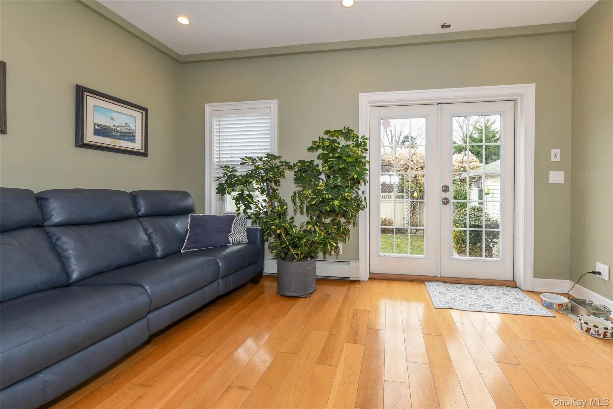 Living area featuring light wood-type flooring, french doors, plenty of natural light, baseboard heating, and recessed lighting Living area featuring light wood-type flooring, french doors, plenty of natural light, baseboard heating, and recessed lighting