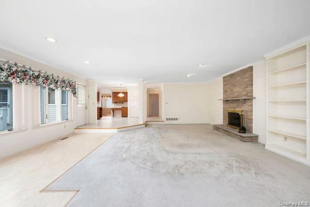 Spacious living area with dining area off the kitchen. Featuring a brick fireplace with a stone hearth, built-in shelving, recessed lighting, and a bay window Spacious living area with dining area off the kitchen. Featuring a brick fireplace with a stone hearth, built-in shelving, recessed lighting, and a bay window