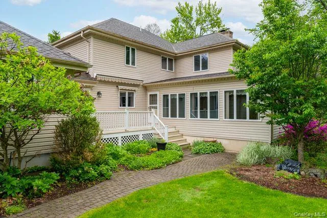 Rear exterior featuring a large sunroom, multi-level deck, and a paver pathway Rear exterior featuring a large sunroom, multi-level deck, and a paver pathway