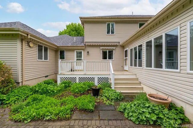 Multi-level exterior deck with white railing, brick paver patio, stone pavers, and established ground cover plantings Multi-level exterior deck with white railing, brick paver patio, stone pavers, and established ground cover plantings