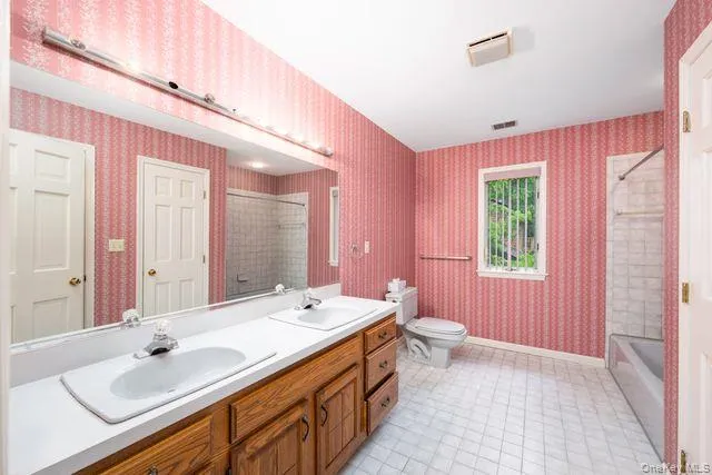 Bathroom, 2nd floor, featuring a dual-sink vanity with wood cabinetry, a large mirror, and overhead strip lighting Bathroom, 2nd floor, featuring a dual-sink vanity with wood cabinetry, a large mirror, and overhead strip lighting