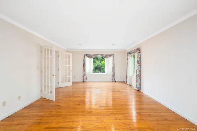 Spacious interior room featuring hardwood flooring and white crown molding Spacious interior room featuring hardwood flooring and white crown molding