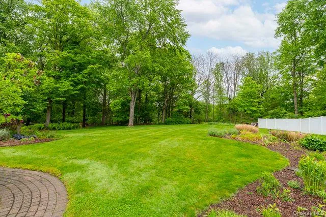 Expansive lawn area bordered by mature trees and a white privacy fence Expansive lawn area bordered by mature trees and a white privacy fence