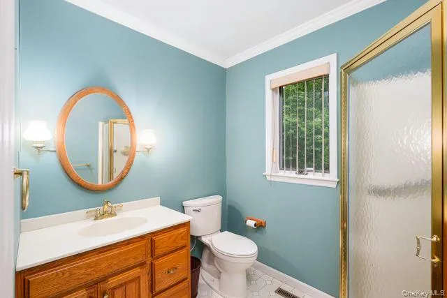 First floor Full Bathroom featuring a honey oak vanity with integrated sink, a gold-framed shower enclosure, hexagon-tiled flooring, and a window with blinds First floor Full Bathroom featuring a honey oak vanity with integrated sink, a gold-framed shower enclosure, hexagon-tiled flooring, and a window with blinds