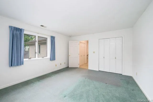 Spacious room featuring a large window, a double bi-fold closet, and wall-to-wall carpeting Spacious room featuring a large window, a double bi-fold closet, and wall-to-wall carpeting