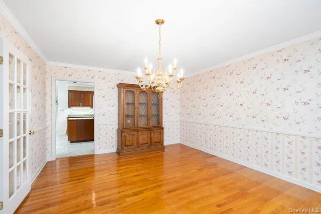 Hardwood flooring throughout, crown molding, and a chandelier fixture Hardwood flooring throughout, crown molding, and a chandelier fixture
