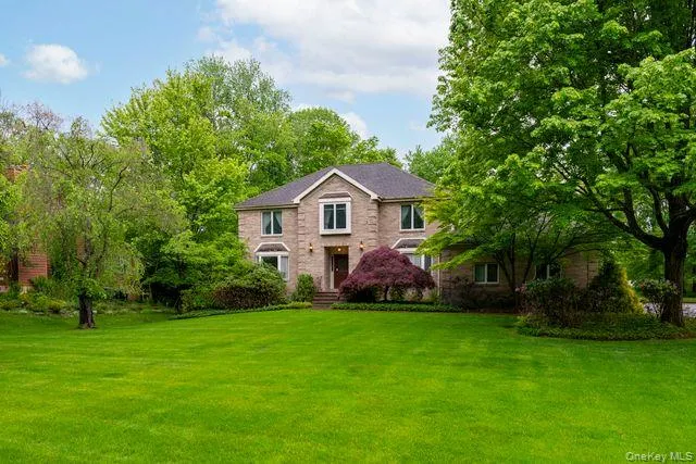 Brick facade residence featuring multiple windows, a prominent front door, and a dark shingle roof Brick facade residence featuring multiple windows, a prominent front door, and a dark shingle roof