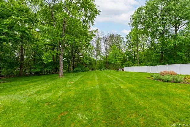 Expansive green lawn with mature trees bordering the property, and established shrubbery Expansive green lawn with mature trees bordering the property, and established shrubbery