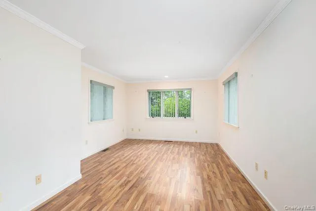 First Floor Spacious room (Office, Guest or Primary) featuring wood-finish flooring, white walls, and elegant crown molding First Floor Spacious room (Office, Guest or Primary) featuring wood-finish flooring, white walls, and elegant crown molding