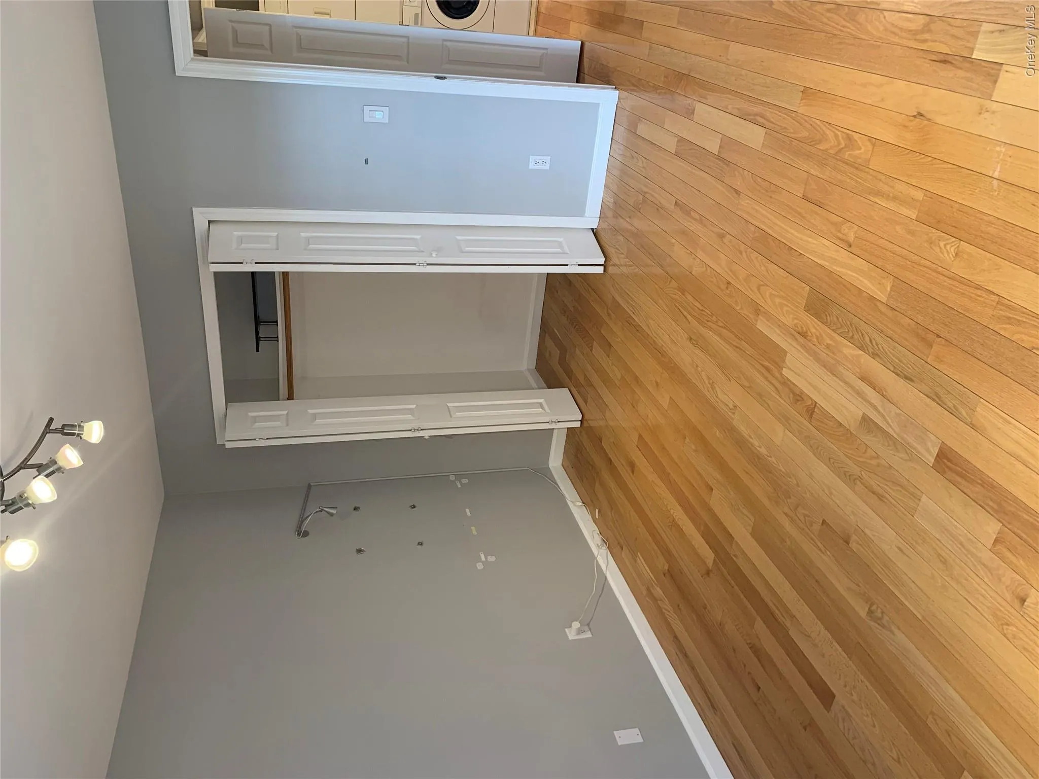Hardwood flooring throughout featuring light gray walls, a bi-fold closet with interior shelving, and a track lighting fixture Hardwood flooring throughout featuring light gray walls, a bi-fold closet with interior shelving, and a track lighting fixture