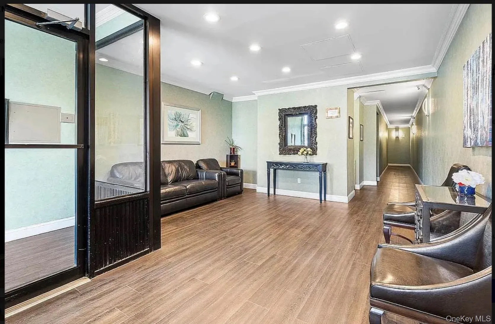 Spacious entry area featuring wood-finish flooring, recessed lighting, crown molding, and a long hallway with sconce lighting Spacious entry area featuring wood-finish flooring, recessed lighting, crown molding, and a long hallway with sconce lighting