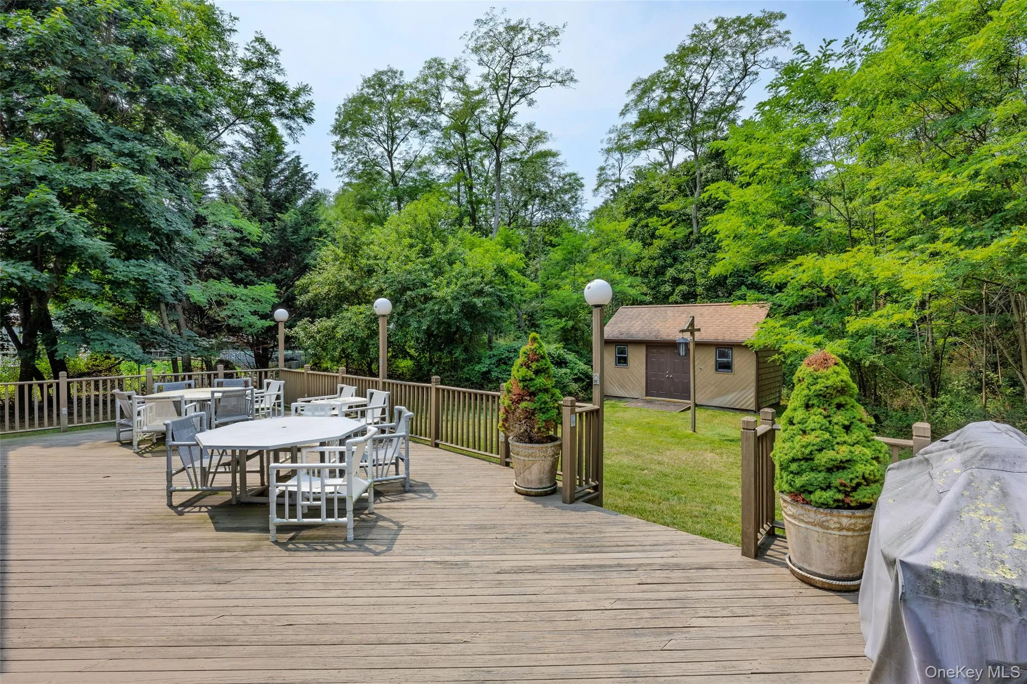 Expansive wood deck with a perimeter railing, integrated lighting, and a separate storage shed. Expansive wood deck with a perimeter railing, integrated lighting, and a separate storage shed.