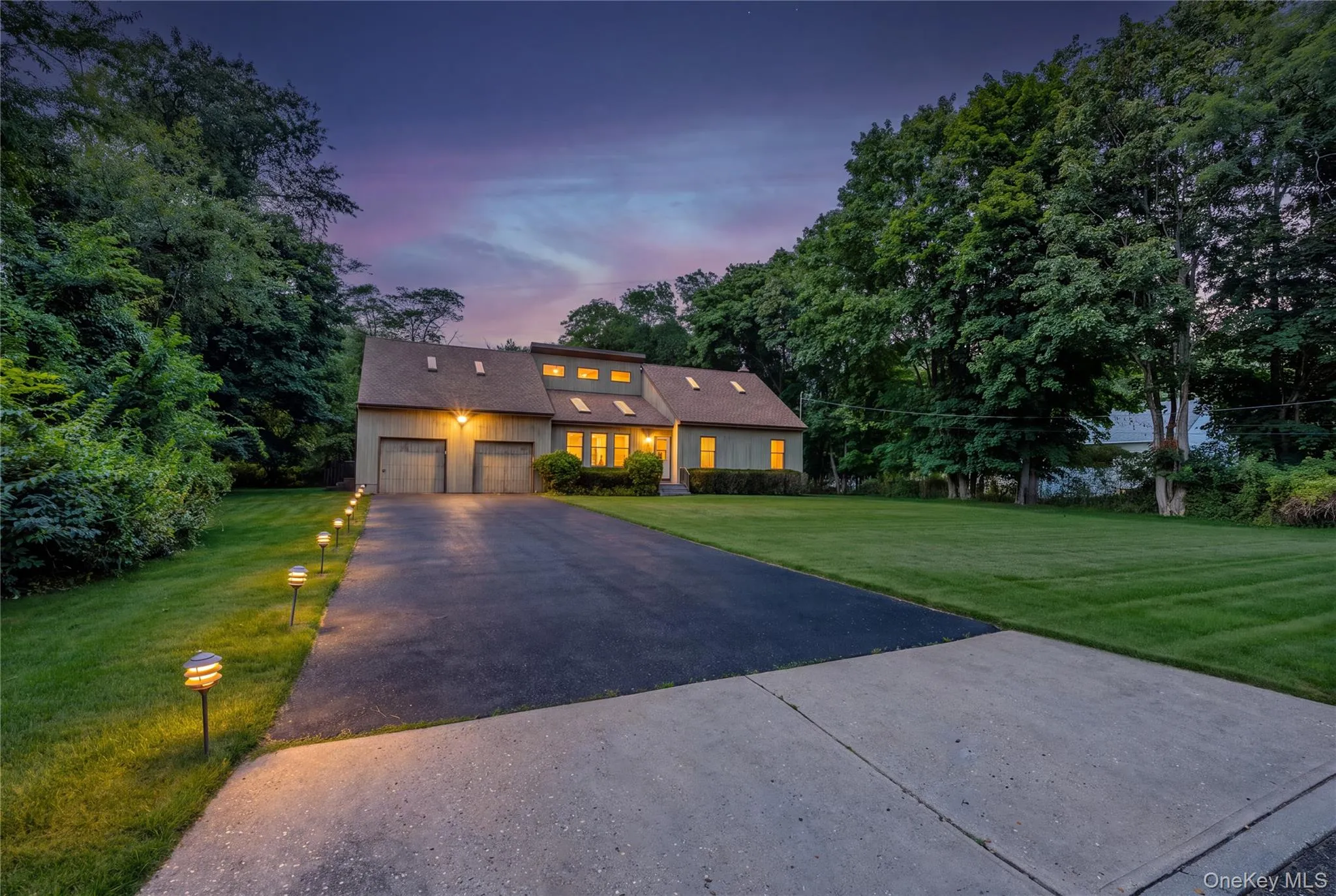 Expansive paved driveway with path lighting, mature trees, and a two-car garage*Digitally enhanced Expansive paved driveway with path lighting, mature trees, and a two-car garage*Digitally enhanced