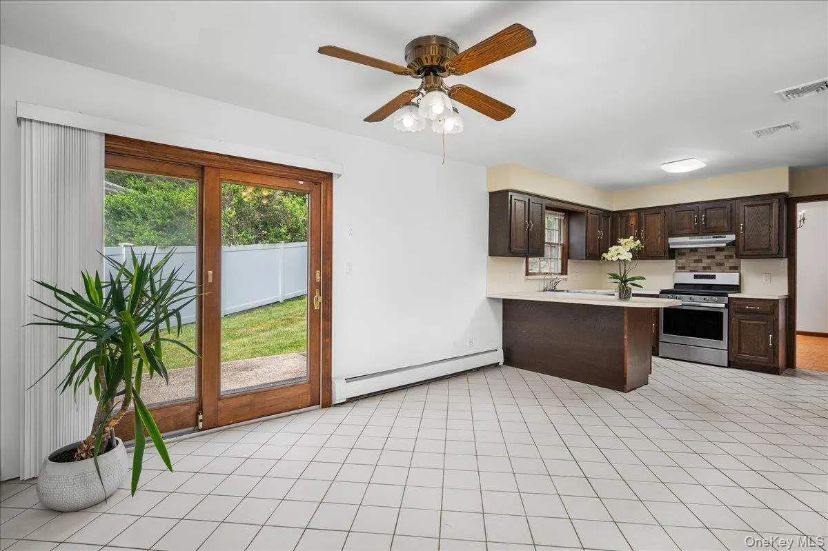 Kitchen area featuring a breakfast bar with light-toned countertops, dark wood-finish cabinetry, and stainless steel appliances Kitchen area featuring a breakfast bar with light-toned countertops, dark wood-finish cabinetry, and stainless steel appliances