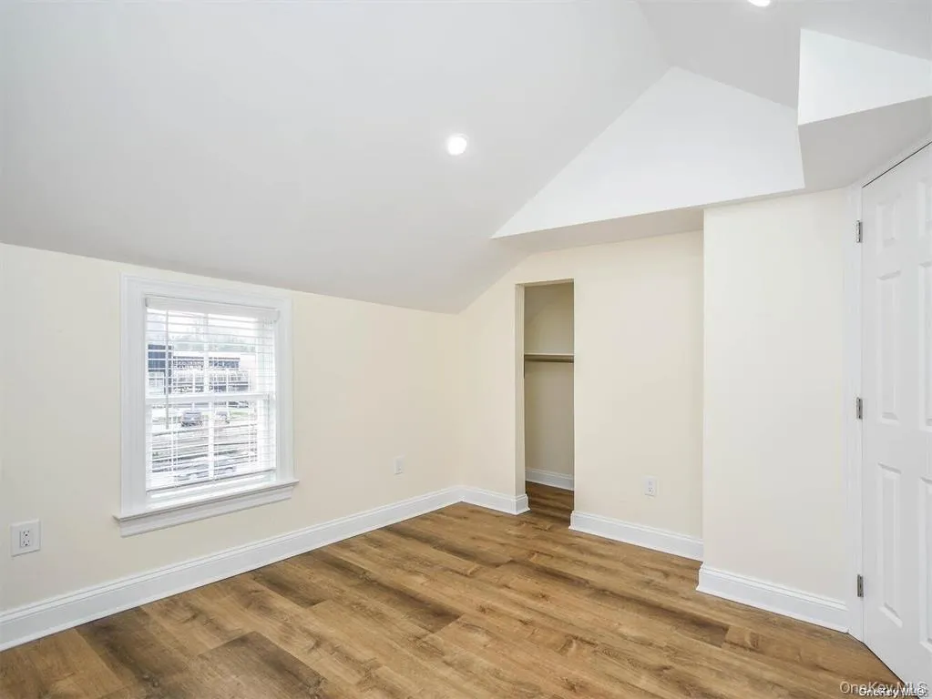 Unfurnished bedroom featuring lofted ceiling, wood finished floors, and baseboards Unfurnished bedroom featuring lofted ceiling, wood finished floors, and baseboards