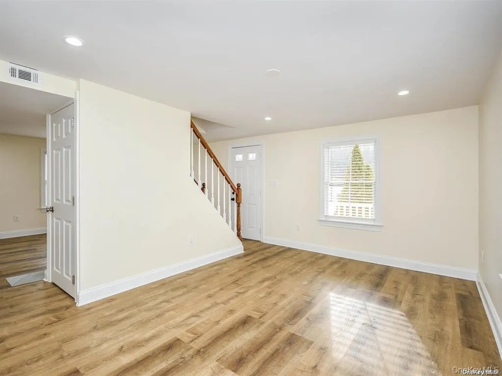 Spare room featuring visible vents, baseboards, light wood-style flooring, and stairway Spare room featuring visible vents, baseboards, light wood-style flooring, and stairway
