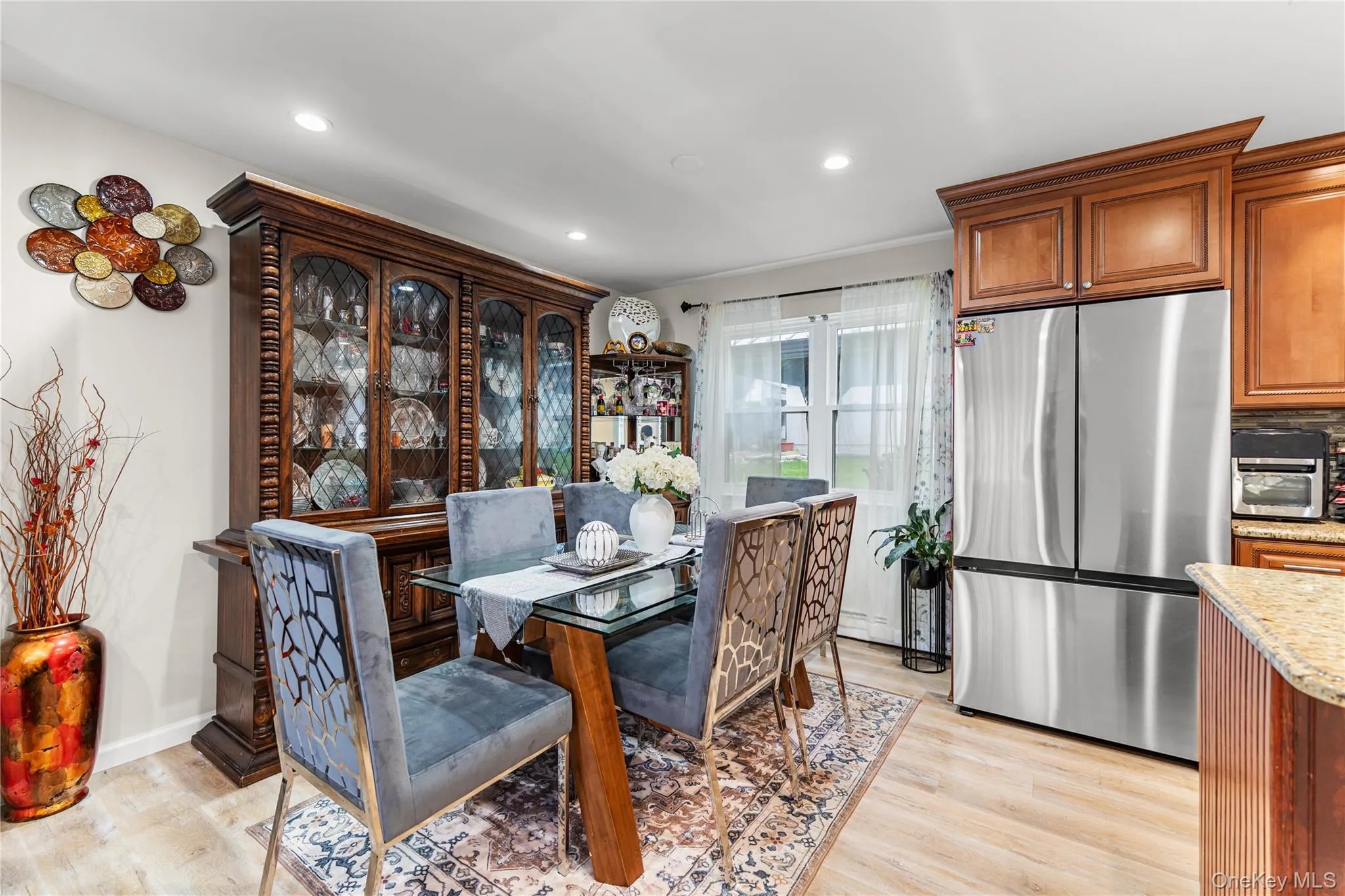 Dining area featuring wood-finish flooring, recessed lighting, and a window with white sheer curtains Dining area featuring wood-finish flooring, recessed lighting, and a window with white sheer curtains
