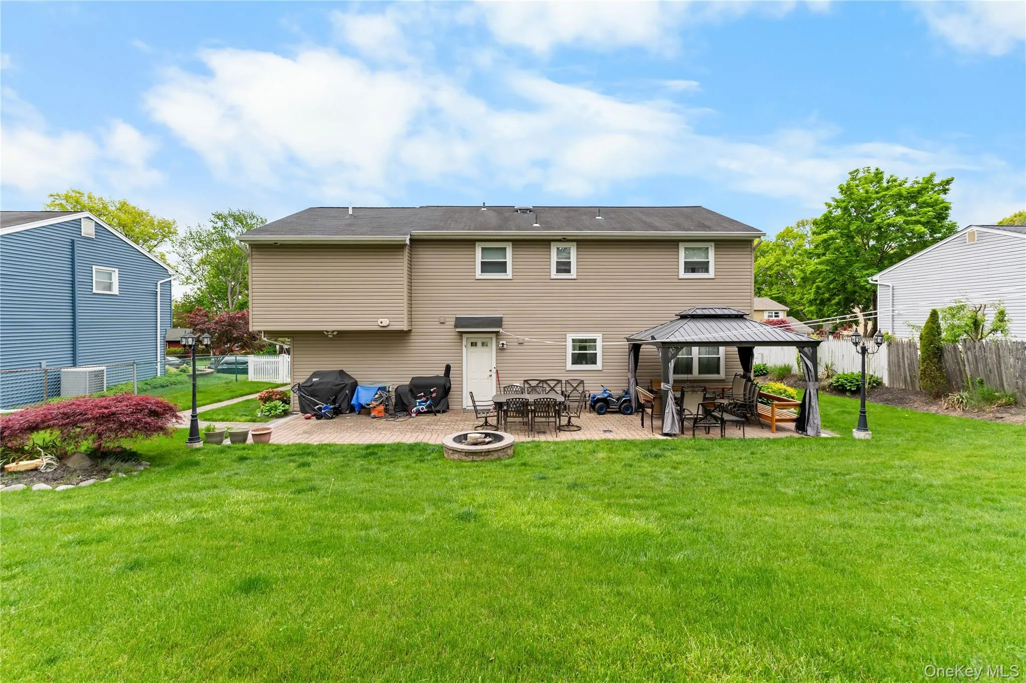 Expansive rear yard featuring a large green lawn and a paver patio Expansive rear yard featuring a large green lawn and a paver patio