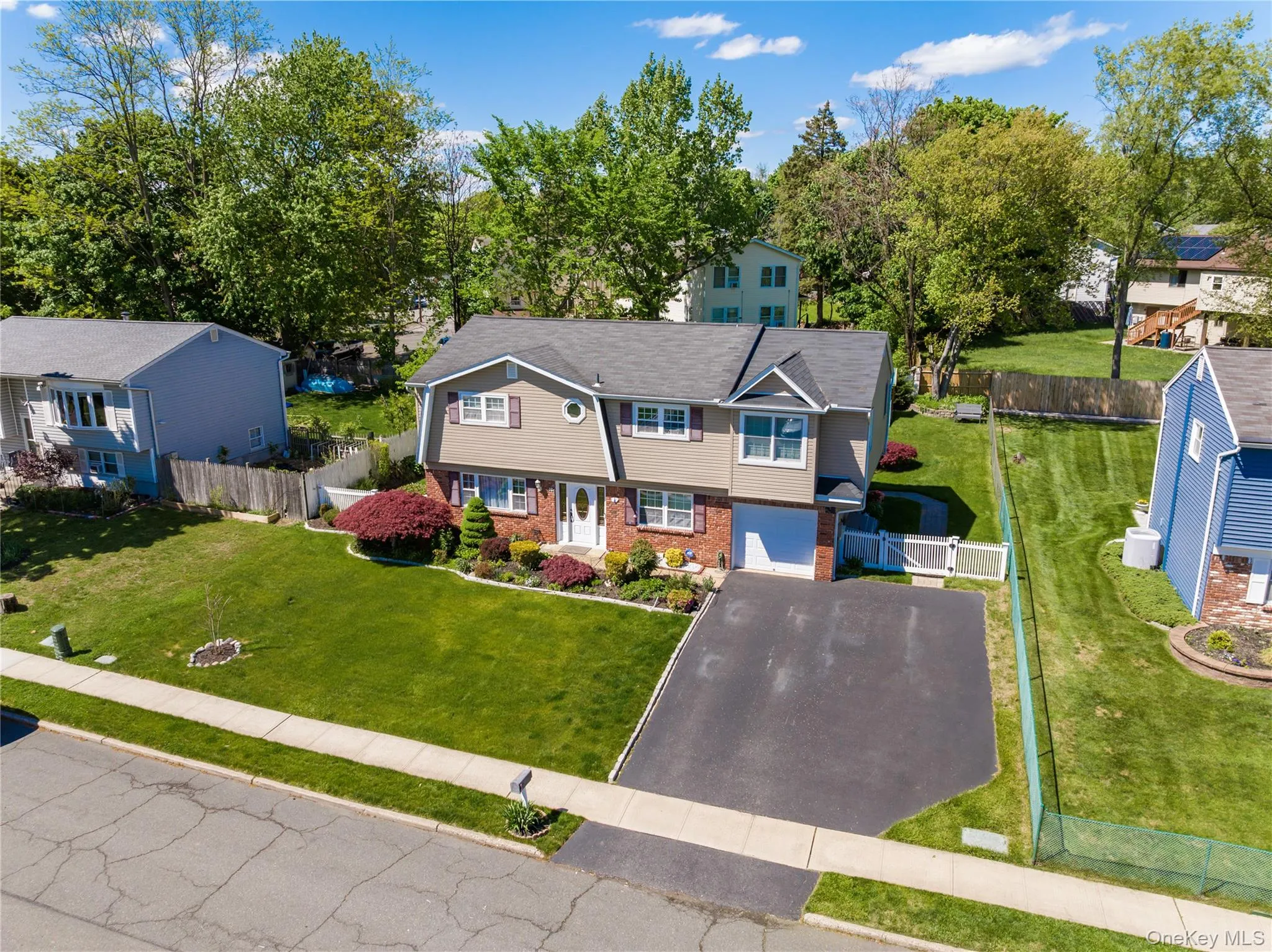 Two-story residence featuring a combination of brick and siding, an attached garage, and a paved driveway Two-story residence featuring a combination of brick and siding, an attached garage, and a paved driveway