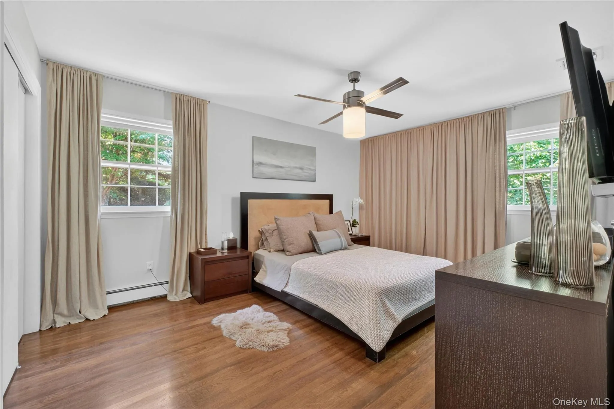 Relax in the large primary bedroom with southern and western exposures, and a beautifully upgraded bathroom with rainfall shower Relax in the large primary bedroom with southern and western exposures, and a beautifully upgraded bathroom with rainfall shower