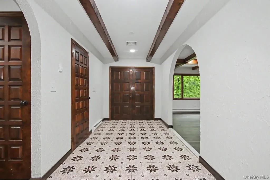 Entryway featuring patterned tile flooring, exposed wood ceiling beams, and arched doorways Entryway featuring patterned tile flooring, exposed wood ceiling beams, and arched doorways