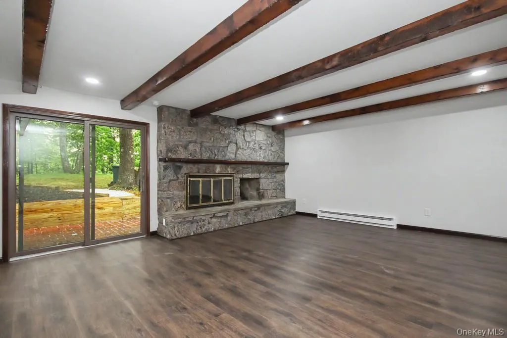 Spacious living area featuring wood-finish flooring, exposed ceiling beams, and recessed lighting Spacious living area featuring wood-finish flooring, exposed ceiling beams, and recessed lighting