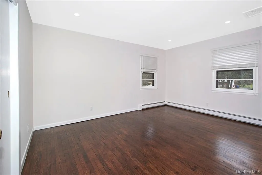 Bedroom featuring dark wood-finish flooring, windows and recessed ceiling lighting Bedroom featuring dark wood-finish flooring, windows and recessed ceiling lighting