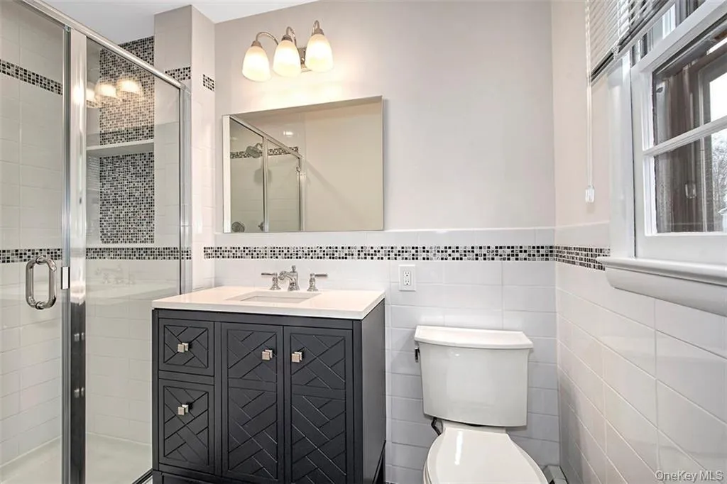 Bathroom featuring a glass-enclosed shower, dark wood vanity and tile accents Bathroom featuring a glass-enclosed shower, dark wood vanity and tile accents
